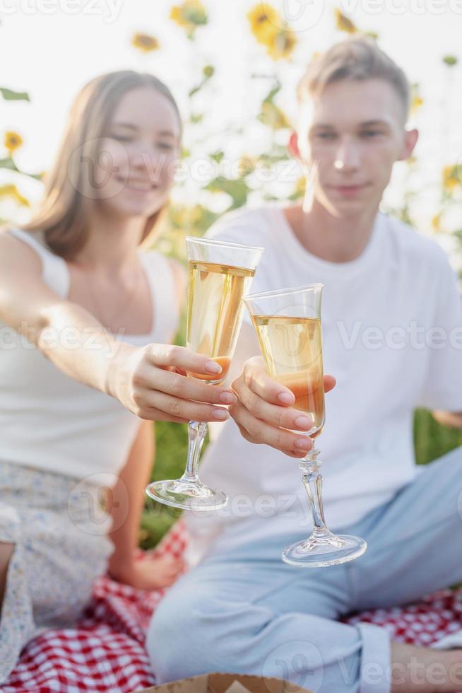 jovem casal fazendo piquenique no campo de girassol ao pôr do sol foto