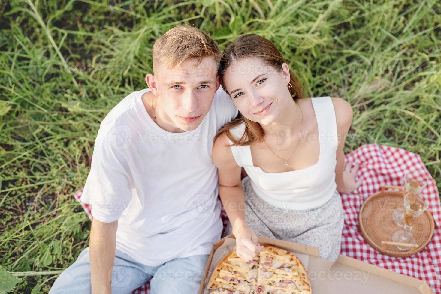 jovem casal fazendo piquenique no campo de girassol ao pôr do sol foto