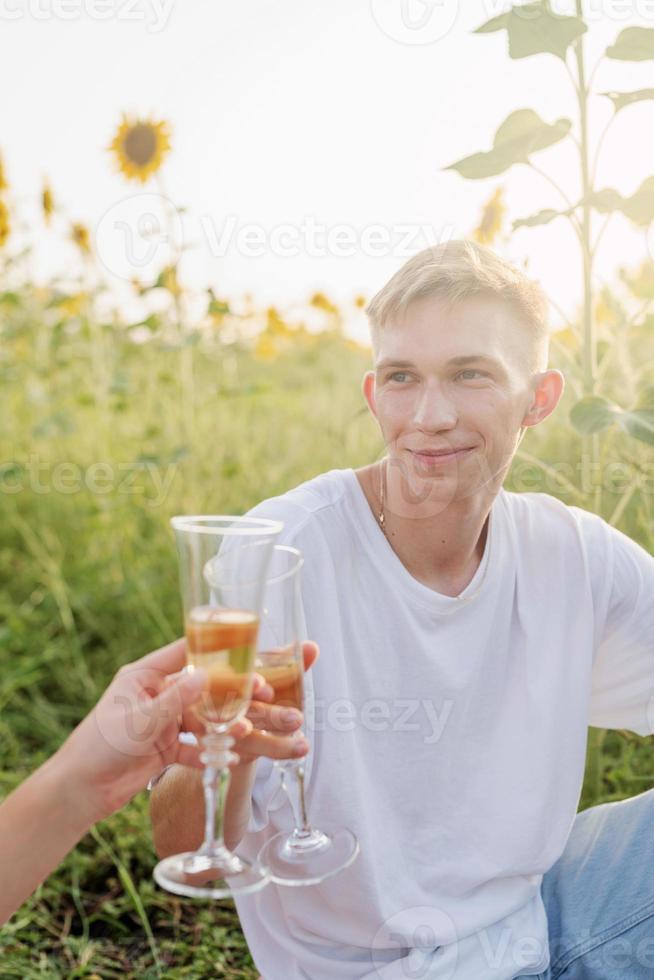 jovem casal fazendo piquenique no campo de girassol ao pôr do sol foto