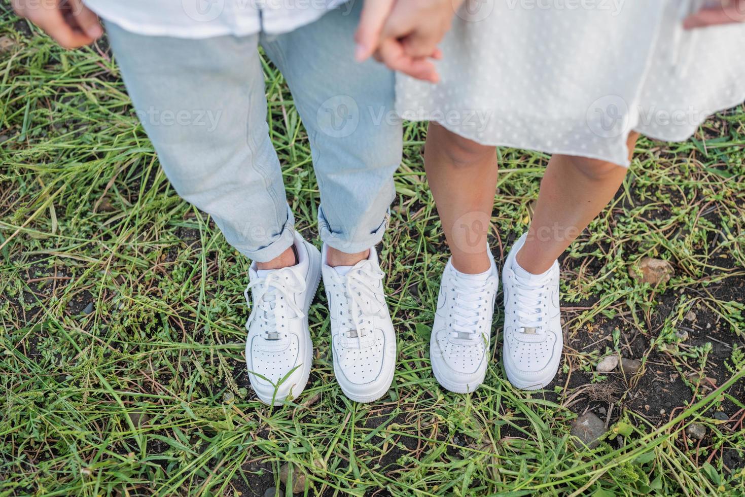 casal em pé no campo de grama. pés e sapatos do jovem casal. foto
