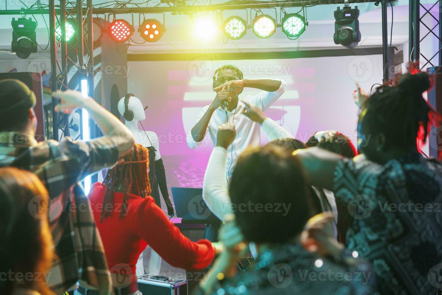 pessoas em pista de dança comovente para ritmo às eletrônico música show dentro Boate. multidão festa, desfrutando vida noturna e dançando enquanto dj cantando e realizando em etapa dentro clube às noite foto