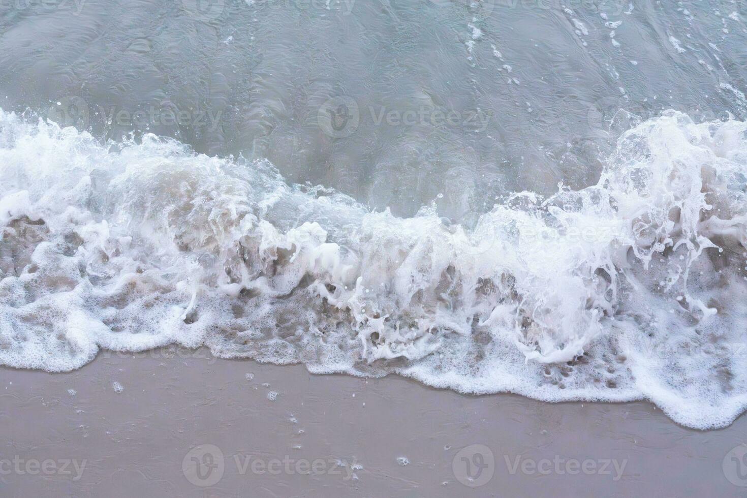 suave onda com bolhas em arenoso de praia foto