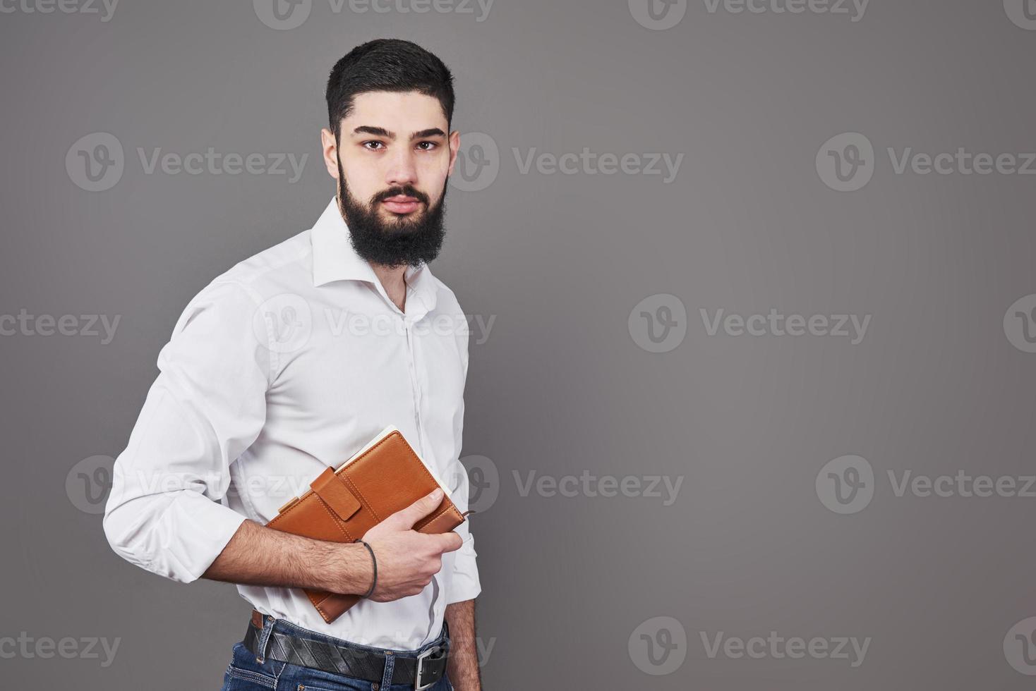 retrato de homem barbudo bonito cheio de dentes com um livro nas mãos foto