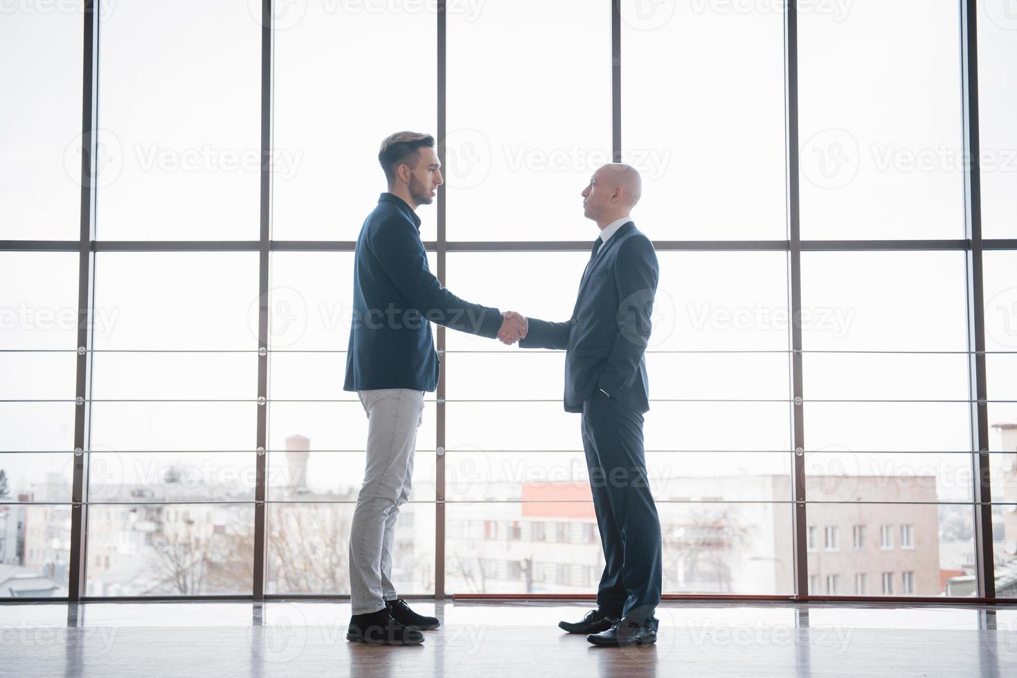 dois confiante homem de negócios apertando as mãos durante uma reunião no escritório, sucesso, negociação, saudação e conceito de parceiro foto