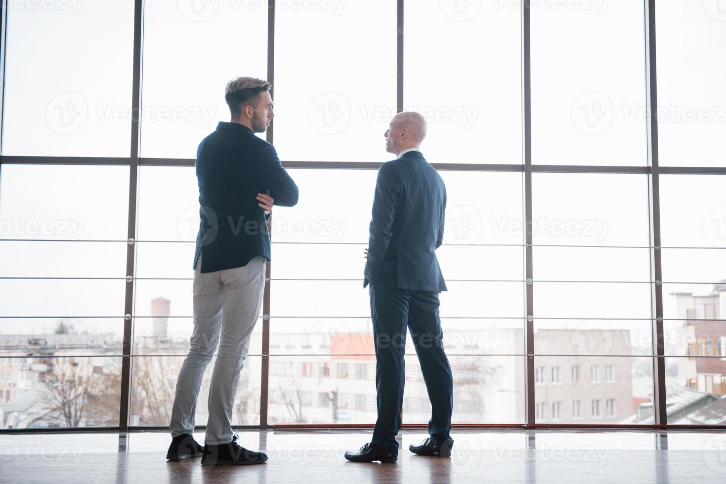 dois empresários em uma discussão profunda enquanto estavam em uma sala de reuniões com janelas com vista para a cidade foto