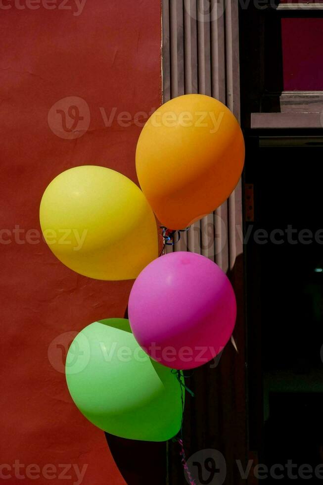 colorida balões suspensão a partir de uma vermelho parede foto