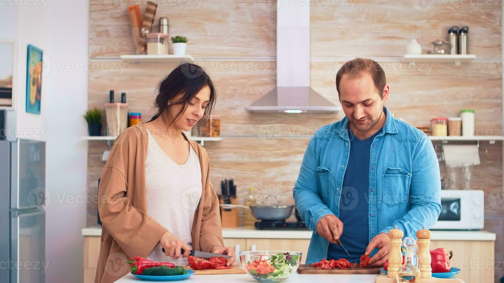 casal cortar tomates em de madeira corte borda para saudável salada dentro cozinha. cozinhando preparando saudável orgânico Comida feliz juntos estilo de vida. alegre refeição dentro família com legumes foto