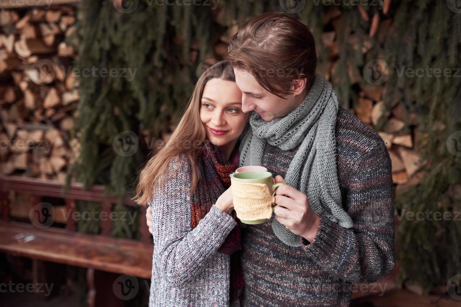 jovem casal tomando café da manhã em uma cabana romântica ao ar livre no inverno. férias e férias de inverno. casal de natal de homem e mulher feliz bebem vinho quente. Casal apaixonado foto