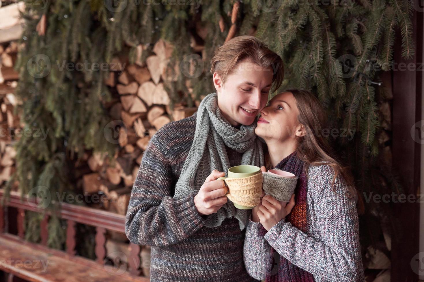 jovem casal tomando café da manhã em uma cabana romântica ao ar livre no inverno. férias e férias de inverno. casal de natal de homem e mulher feliz bebem vinho quente. Casal apaixonado foto