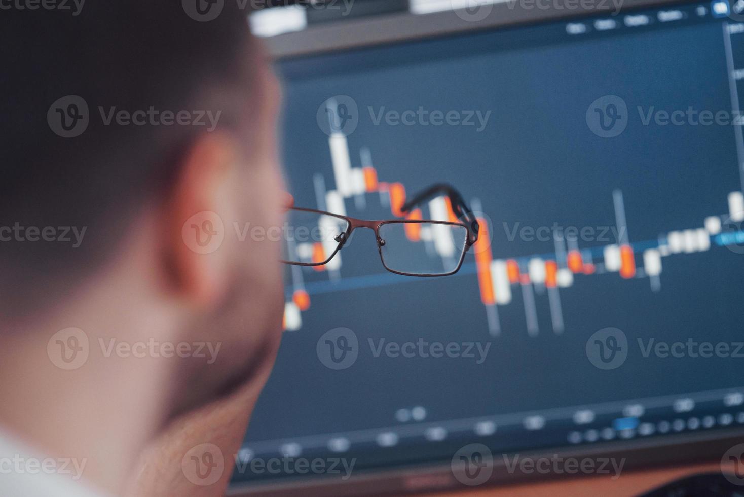 analisando dados. close-up de um jovem empresário que segura óculos e olha para a gff enquanto trabalha em um escritório criativo foto