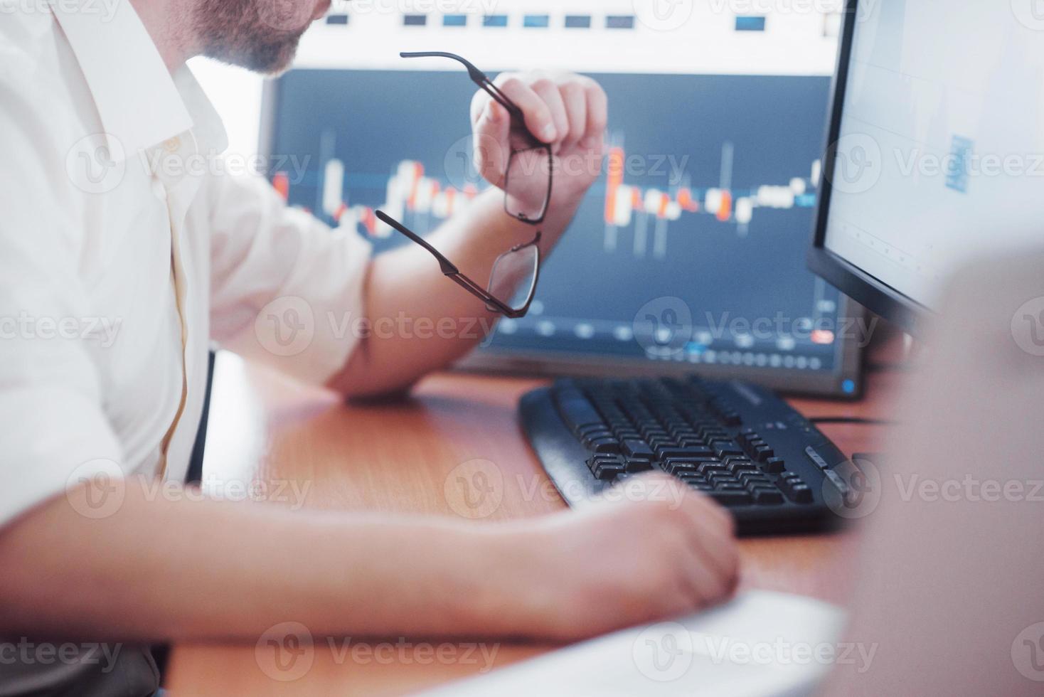 analisando dados. close-up de um jovem empresário que segura óculos e olha para a gff enquanto trabalha em um escritório criativo foto