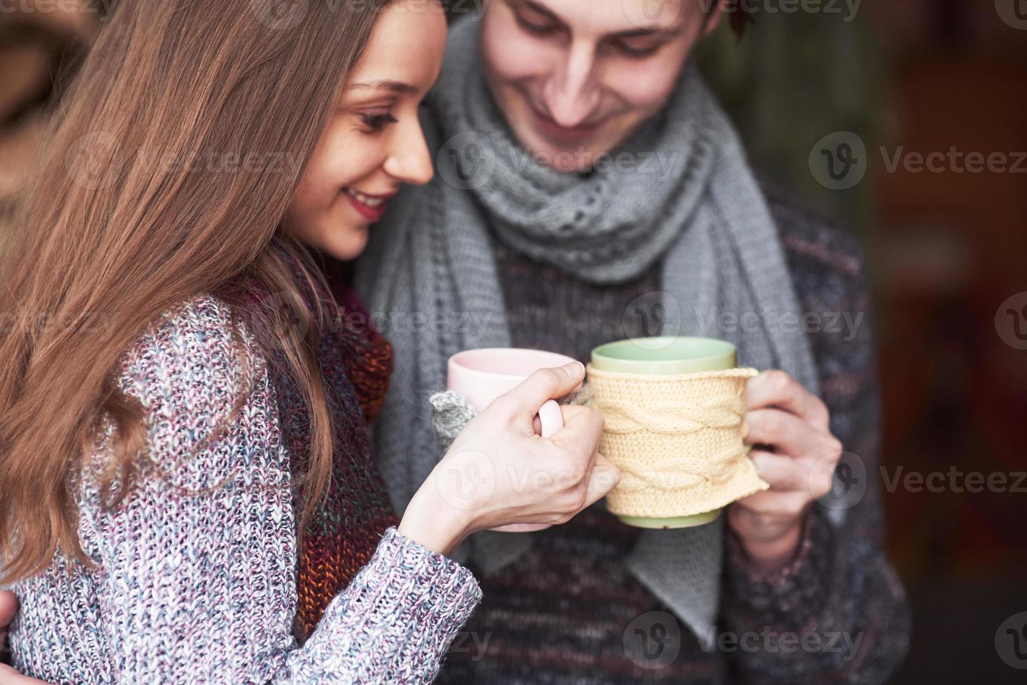 foto de um homem feliz e uma linda mulher com xícaras ao ar livre no inverno. férias e férias de inverno. casal de natal de homem e mulher feliz bebem vinho quente. Casal apaixonado