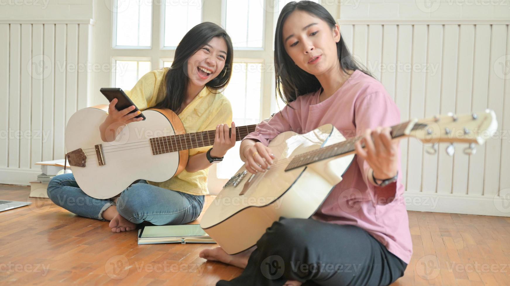 adolescentes asiáticas estão cantando e tocando violão. Elas ficam em casa para evitar o surto do vírus corona. foto