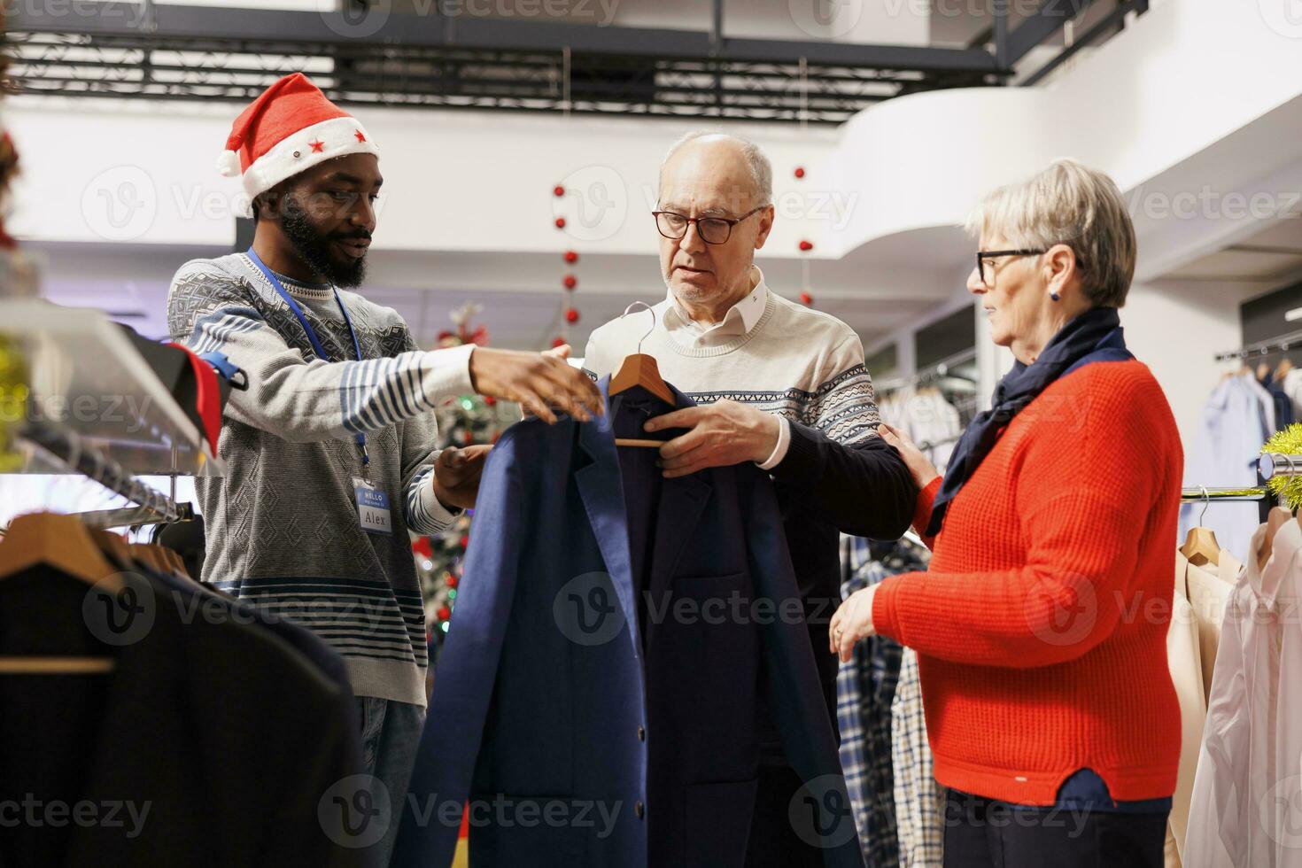homem empregado ajudando clientes para escolher jaquetas e blazers, fazer preparativos para próximos Natal evento. Senior casal compras para roupas dentro varejo loja, comprando mercadoria em oferta. foto