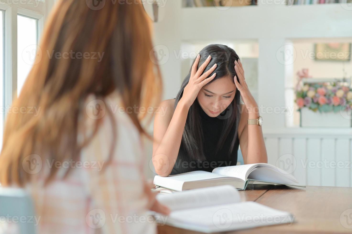 duas alunas asiáticas estão lendo muito para se prepararem para os estudos universitários. foto