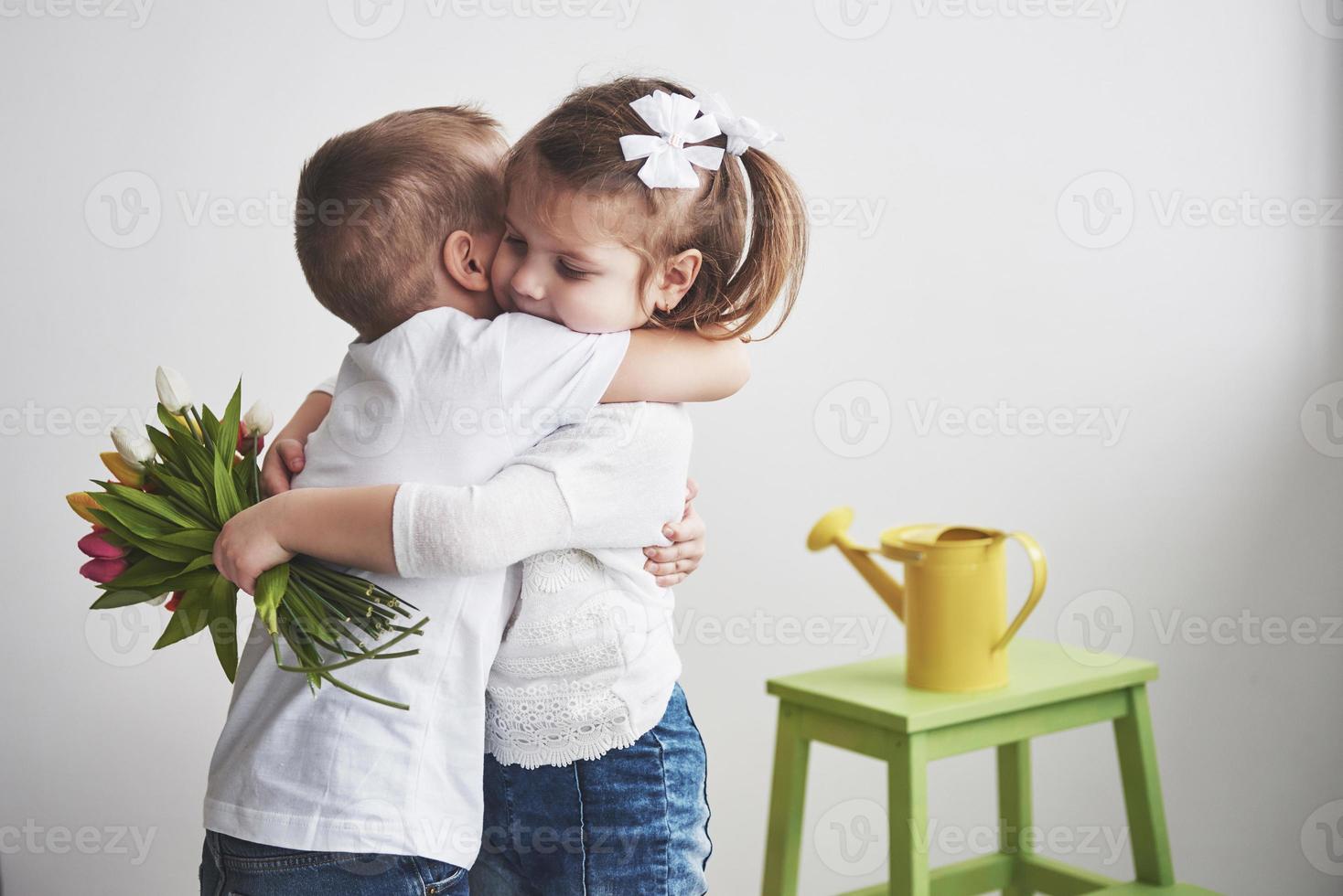 lindo menino e menina com tulipas com um abraço. dia das mães, 8 de março, um feliz aniversário foto