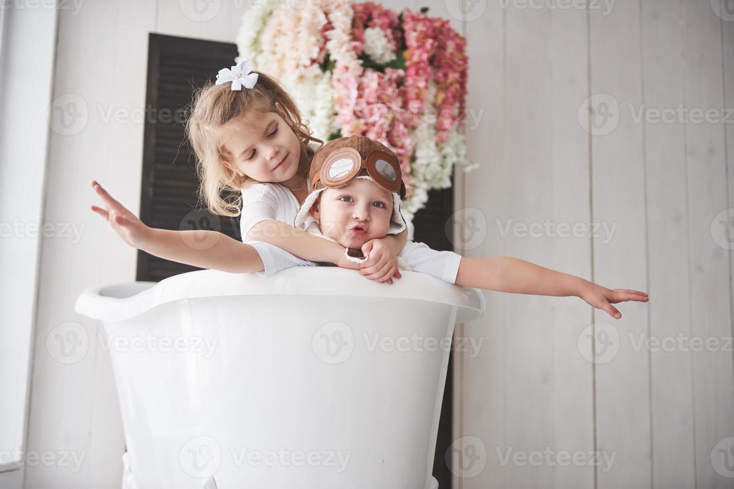 retrato de uma menina e um menino com chapéu de piloto, jogando no banheiro de pilotos ou marinheiros. o conceito de viagem, infância e a realização de sonhos foto