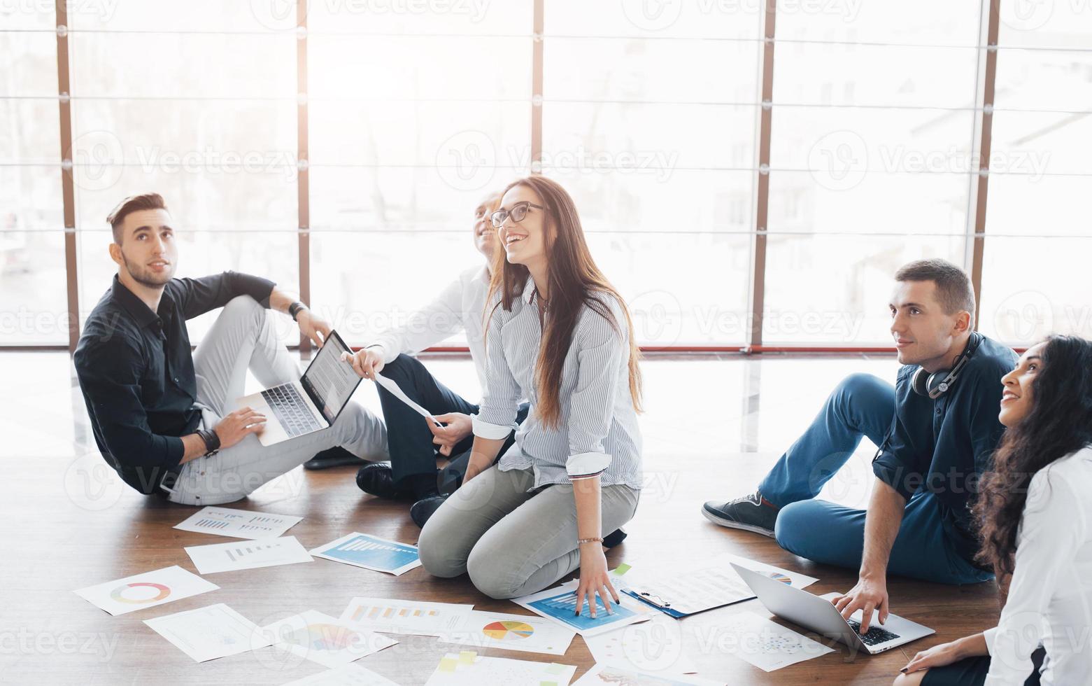 estratégia de planejamento em conjunto. equipe de negócios olhando papéis no chão com o gerente apontando para uma ideia. cooperação realização corporativa. planejamento desenho desenho. conceito de trabalho em equipe foto