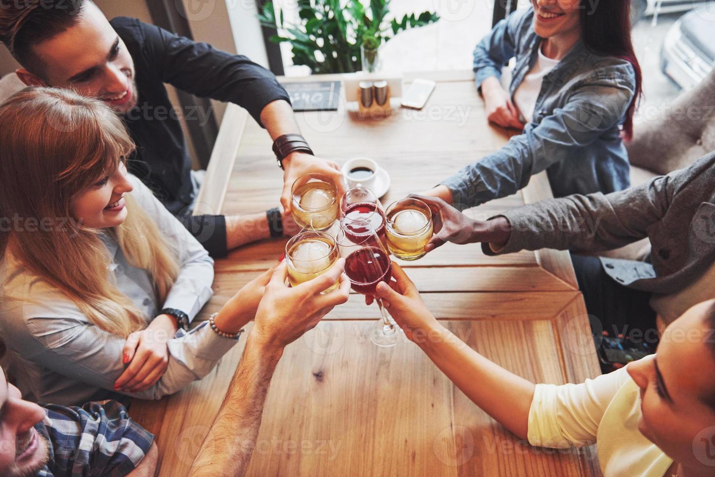 vista de cima. mãos de pessoas com copos de uísque ou vinho, celebrando e brindando em homenagem ao casamento ou outra celebração foto