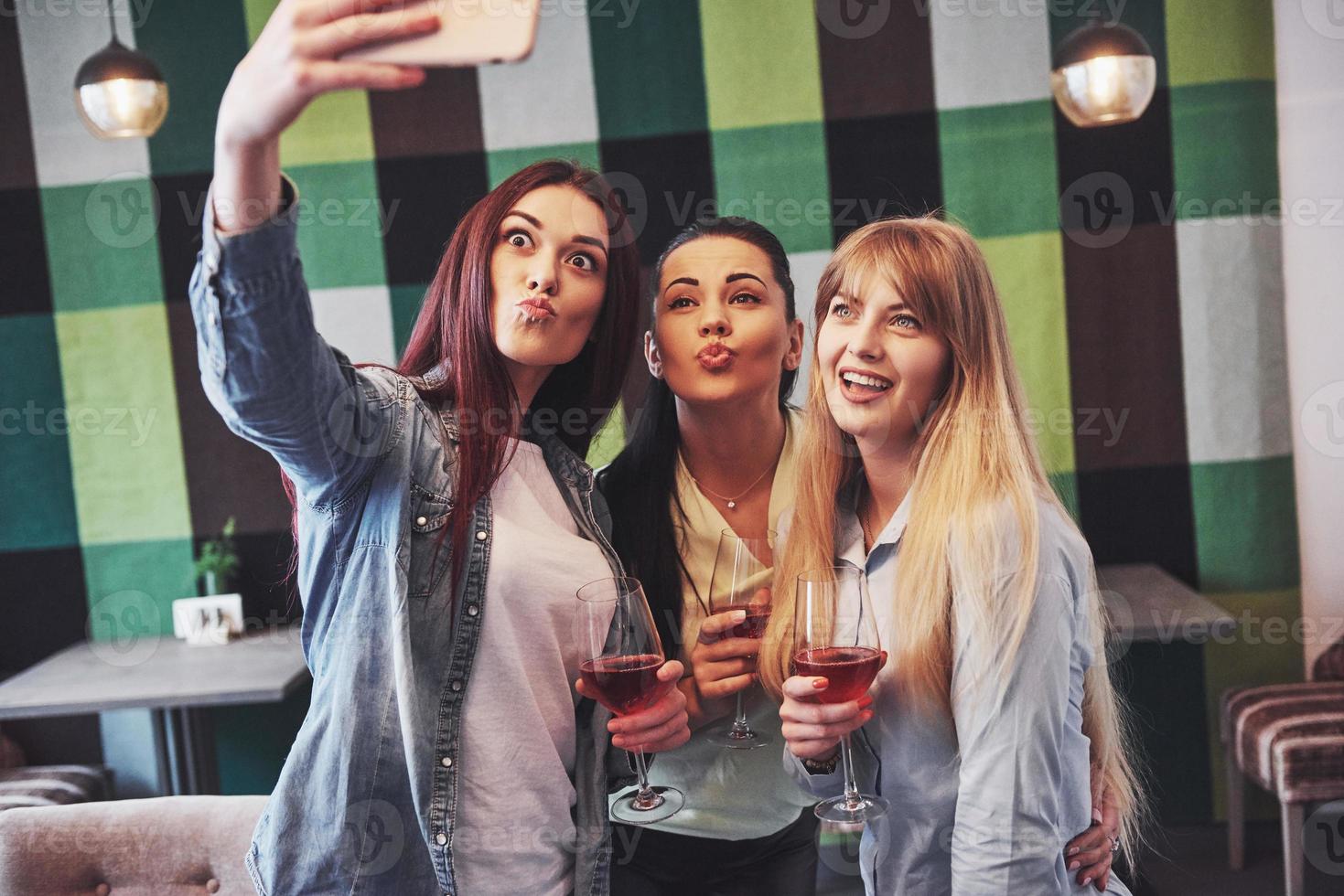 foto apresentando feliz grupo de amigos com vinho tinto tomando selfie
