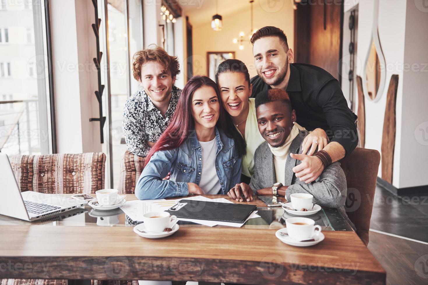 pessoas multirraciais se divertindo no café, tomando uma selfie com o celular. grupo de jovens amigos sentados em restaurante foto