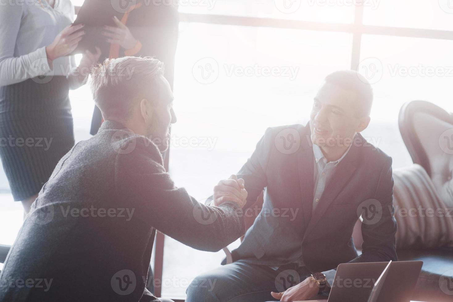 dois confiante homem de negócios apertando as mãos durante uma reunião no escritório, sucesso, negociação, saudação e conceito de parceiro foto