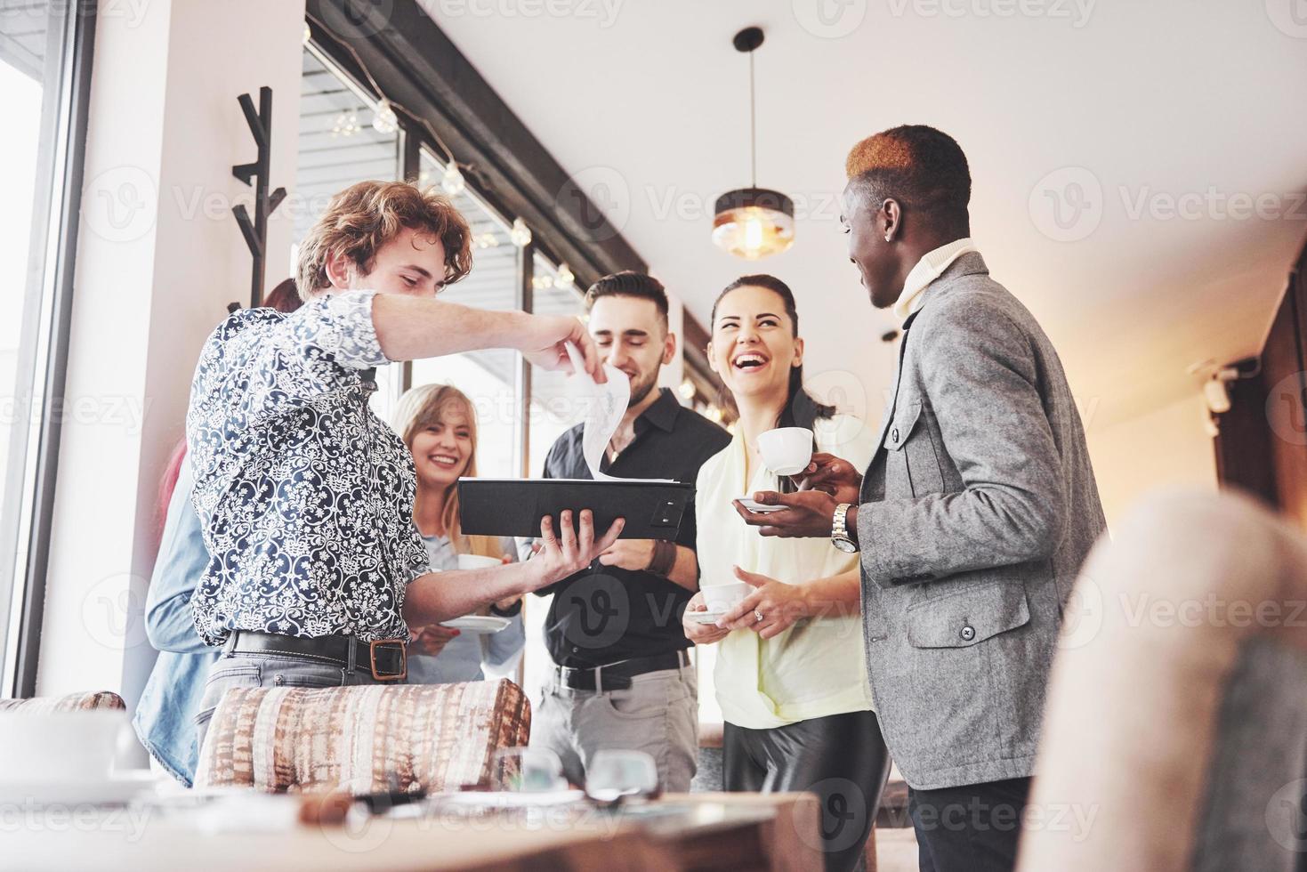 jovens empresários de sucesso estão conversando e sorrindo durante o intervalo para o café no escritório foto