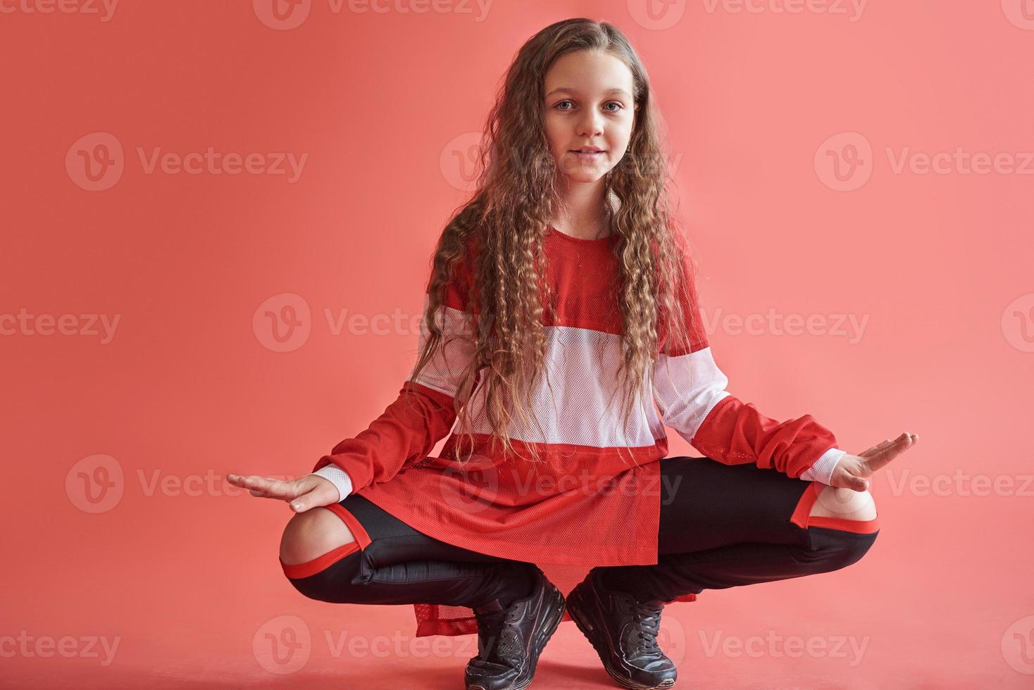 jovem linda linda garota dançando sobre fundo vermelho, estilo hip-hop moderno slim adolescente pulando foto