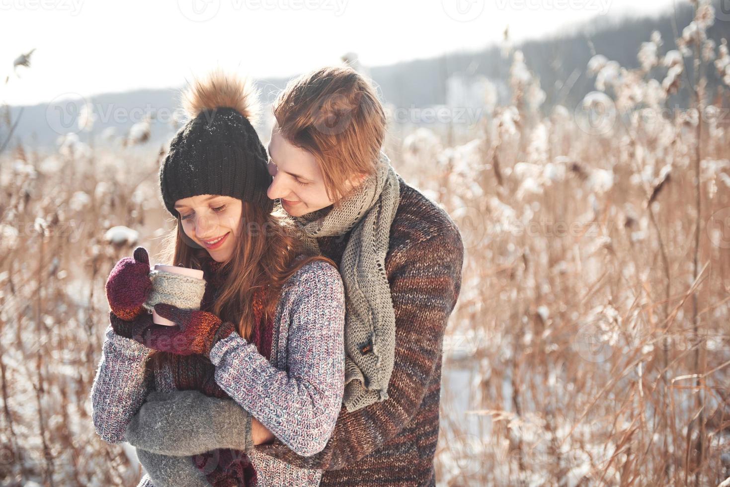 foto de um homem feliz e uma linda mulher com xícaras ao ar livre no inverno. férias e férias de inverno. casal de natal de homem e mulher feliz bebem vinho quente. Casal apaixonado