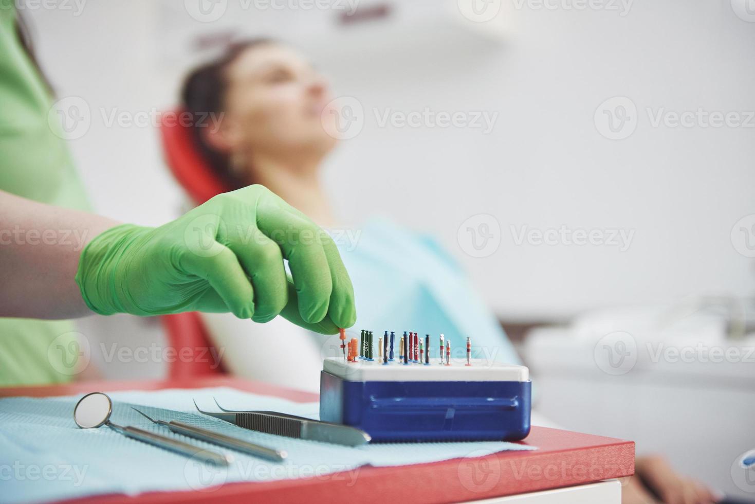 um paciente em uma clínica odontológica se senta em uma cadeira e o médico prepara as ferramentas para o tratamento foto