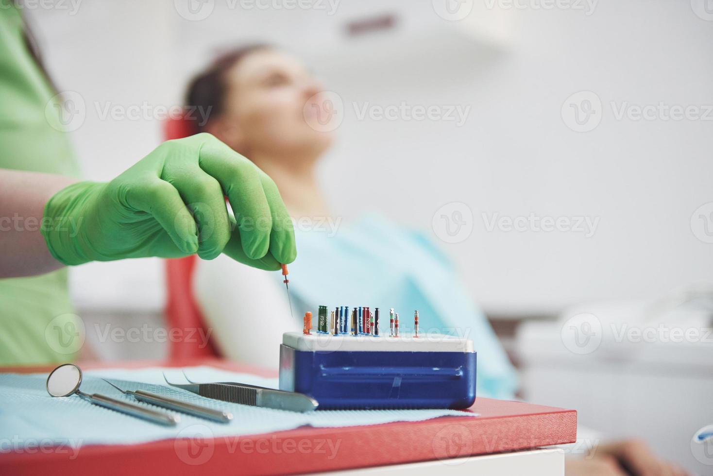 um paciente em uma clínica odontológica se senta em uma cadeira e o médico prepara as ferramentas para o tratamento foto