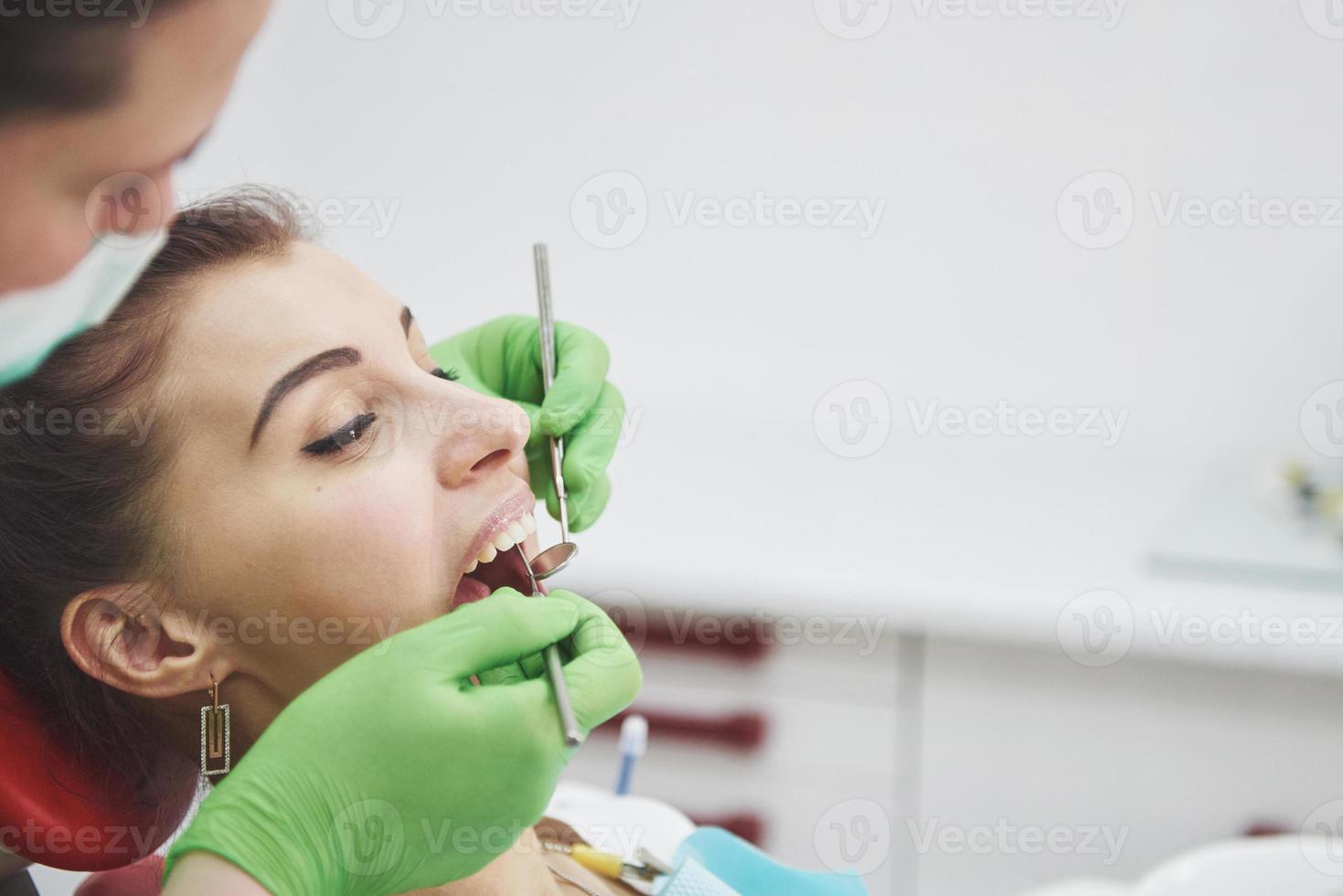 dentista curando uma paciente do sexo feminino na estomatologia. prevenção precoce e conceito de higiene bucal foto