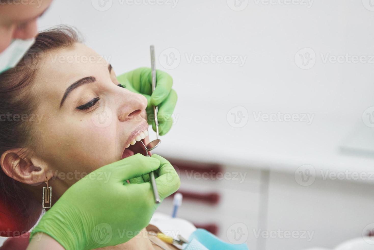 dentista curando uma paciente do sexo feminino na estomatologia. prevenção precoce e conceito de higiene bucal foto