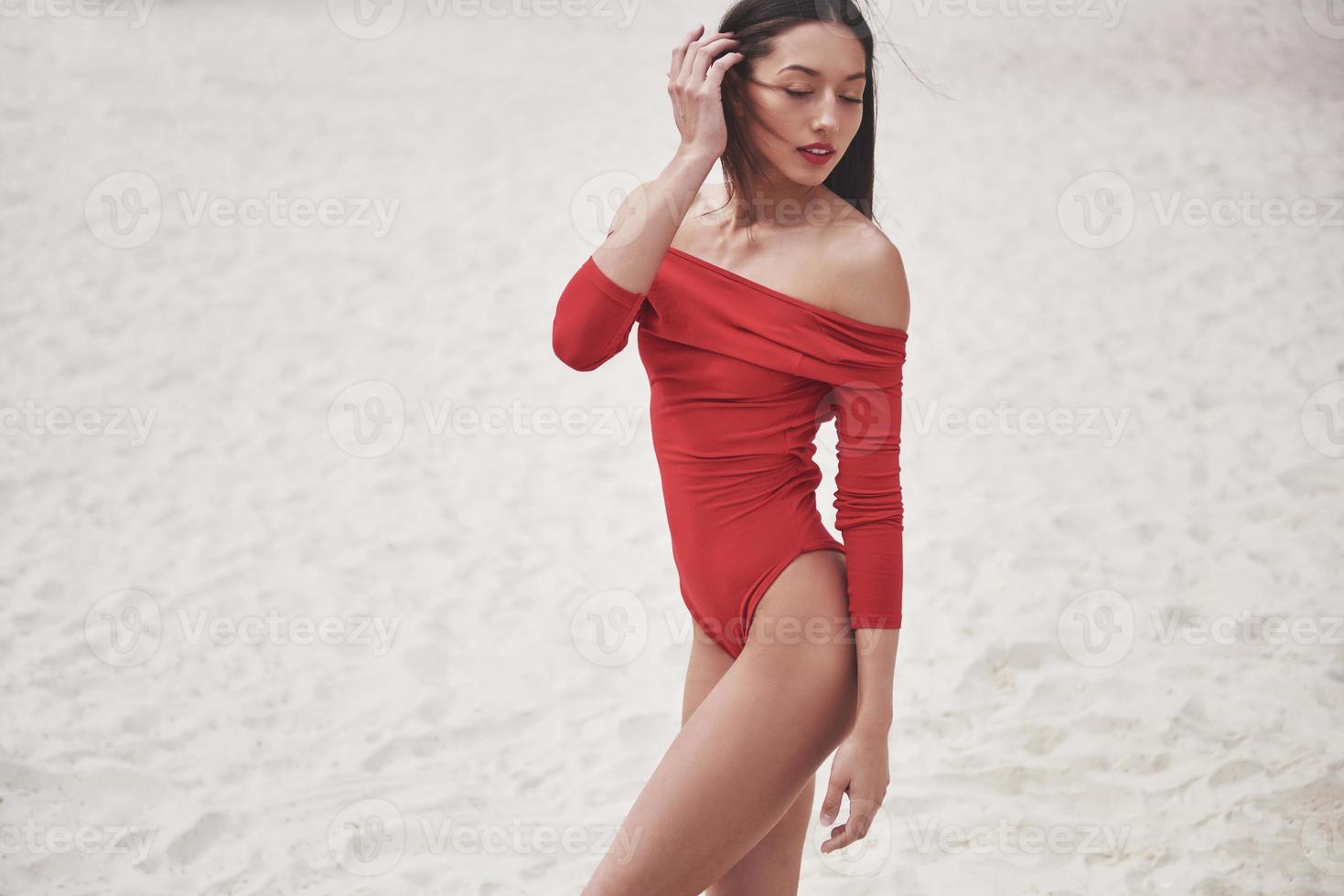 bela jovem bronzeada em biquíni vermelho, posando na praia. retrato de modelo sexy com corpo perfeito. conceito de férias de verão foto