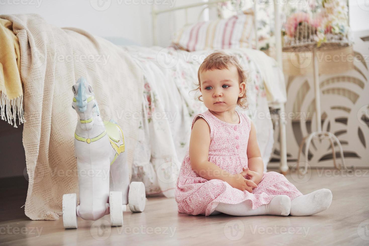 linda garotinha brincando de brinquedos. loira de olhos azuis. cadeira branca. quarto das crianças. retrato de menina feliz. conceito de infância foto