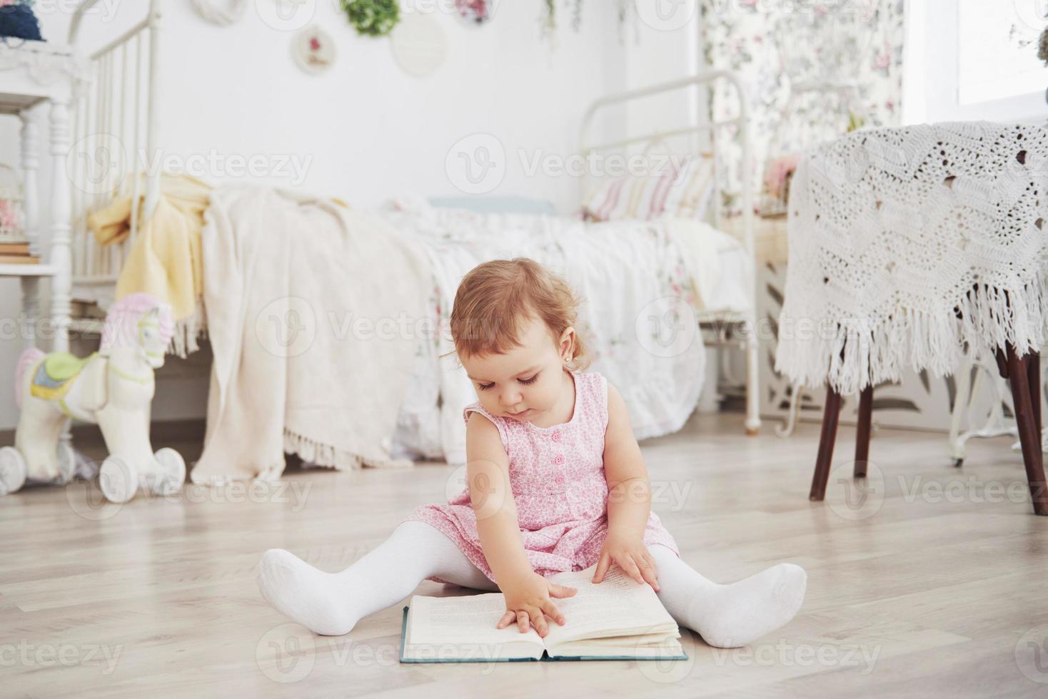 linda garotinha brincando de brinquedos. loira de olhos azuis. cadeira branca. quarto das crianças. retrato de menina feliz. conceito de infância foto