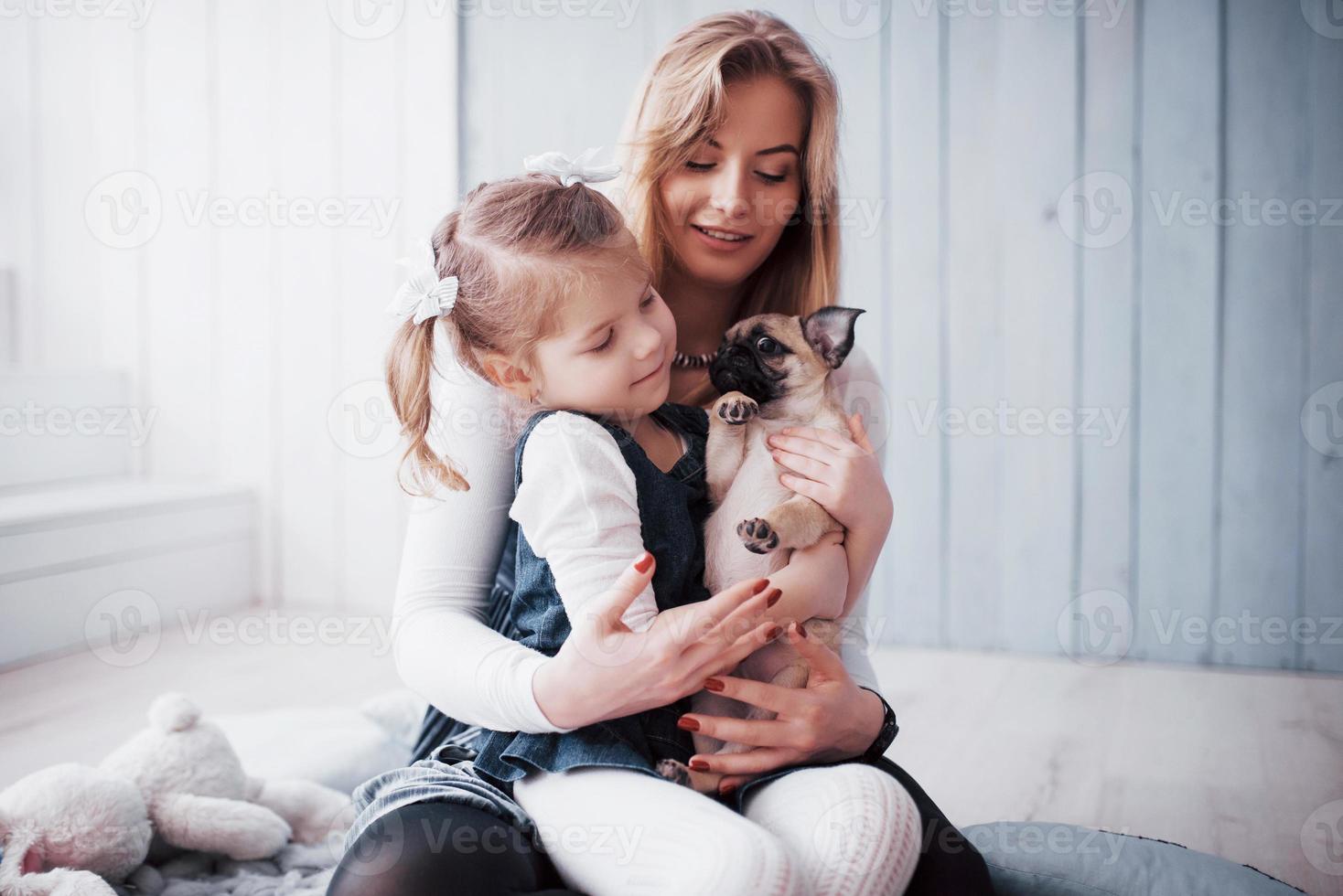 família amorosa feliz. mãe e filha menina brincando e abraçando adorável pug foto