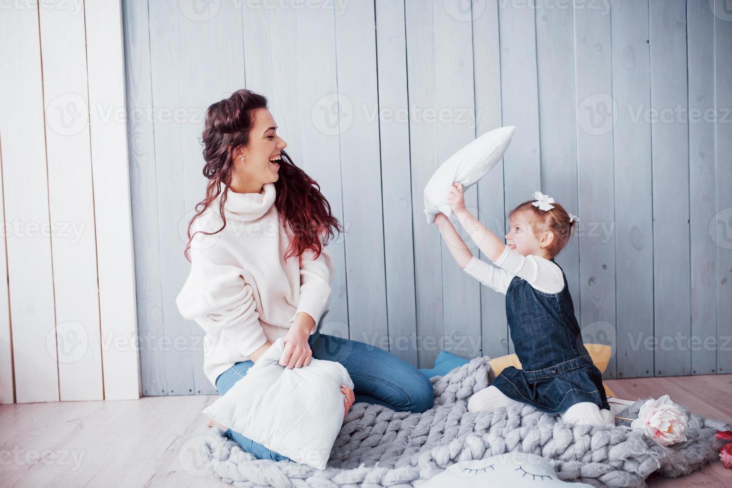 família feliz, a mãe e a filha dela estão lutando contra travesseiros. jogos de família felizes foto