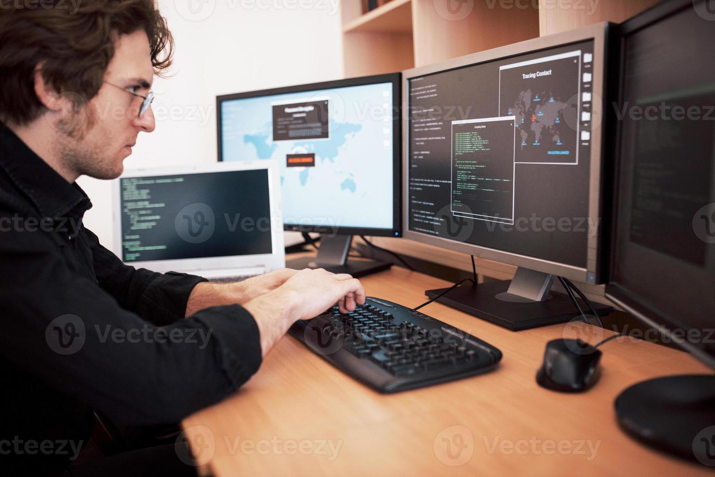 programador masculino trabalhando em um computador desktop com muitos monitores no escritório na empresa de desenvolvimento de software. tecnologias de programação e codificação de design de sites foto