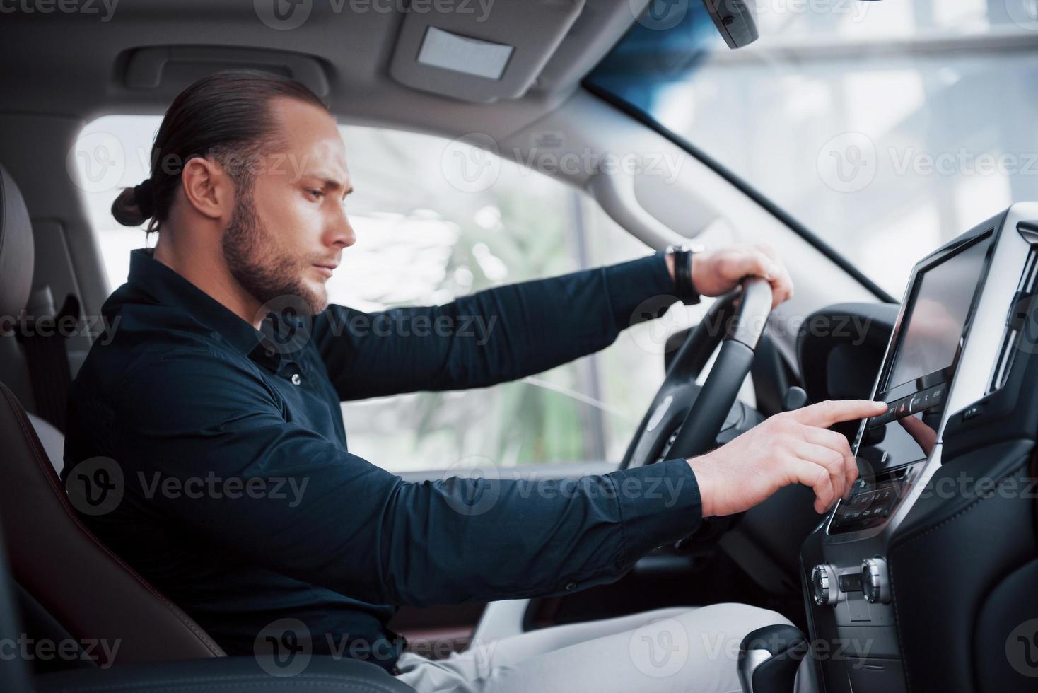 jovem empresário confiante sentado ao volante de seu novo carro foto