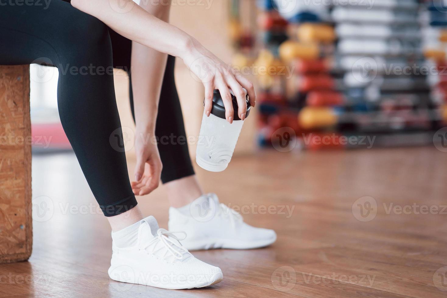 relaxar após o treino. vista de uma bela jovem olhando para longe enquanto está sentado na esteira de exercícios na academia foto