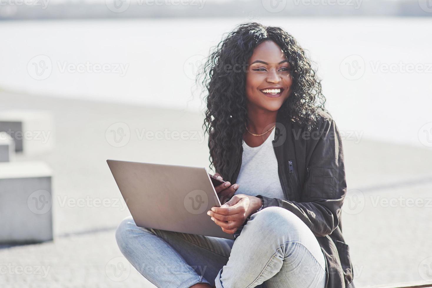 jovem na rua trabalhando em um laptop e falando no celular foto