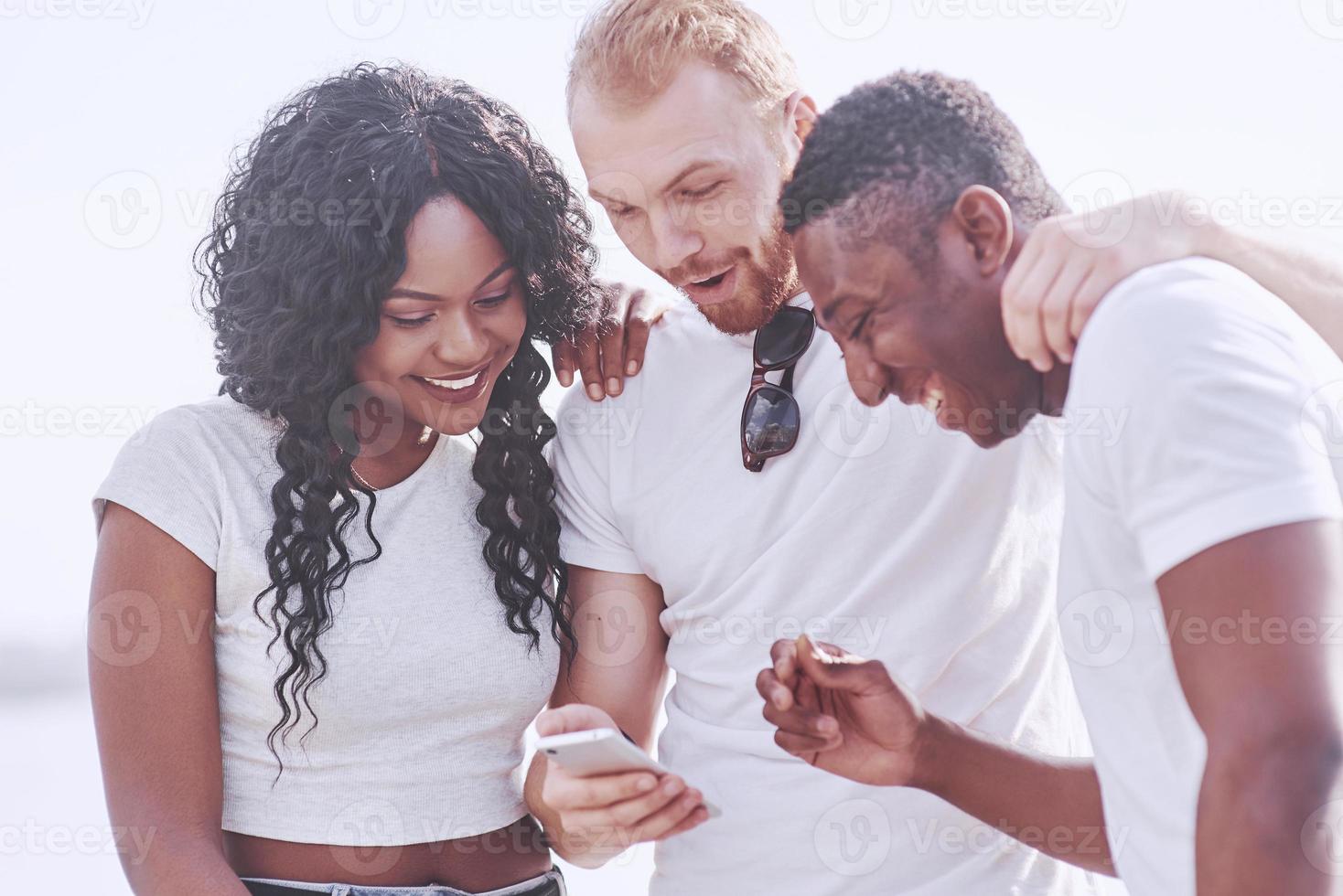 grupo de amigos multirraciais felizes usando o gadget ao ar livre. conceito de felicidade e amizade multiétnica todos juntos contra o racismo foto