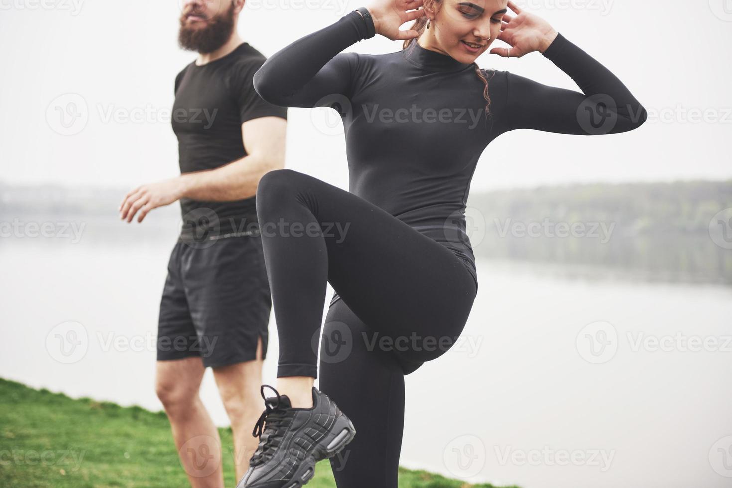 um jovem casal gosta de praticar esportes pela manhã ao ar livre. aquecer antes do exercício foto