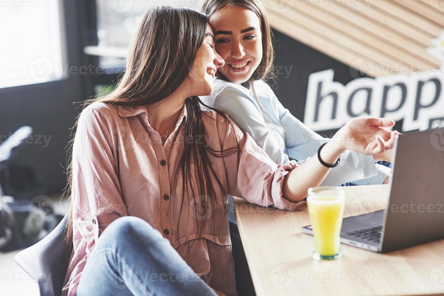 duas lindas gêmeas passam o tempo bebendo suco. irmãs relaxando em um café e se divertindo juntas foto