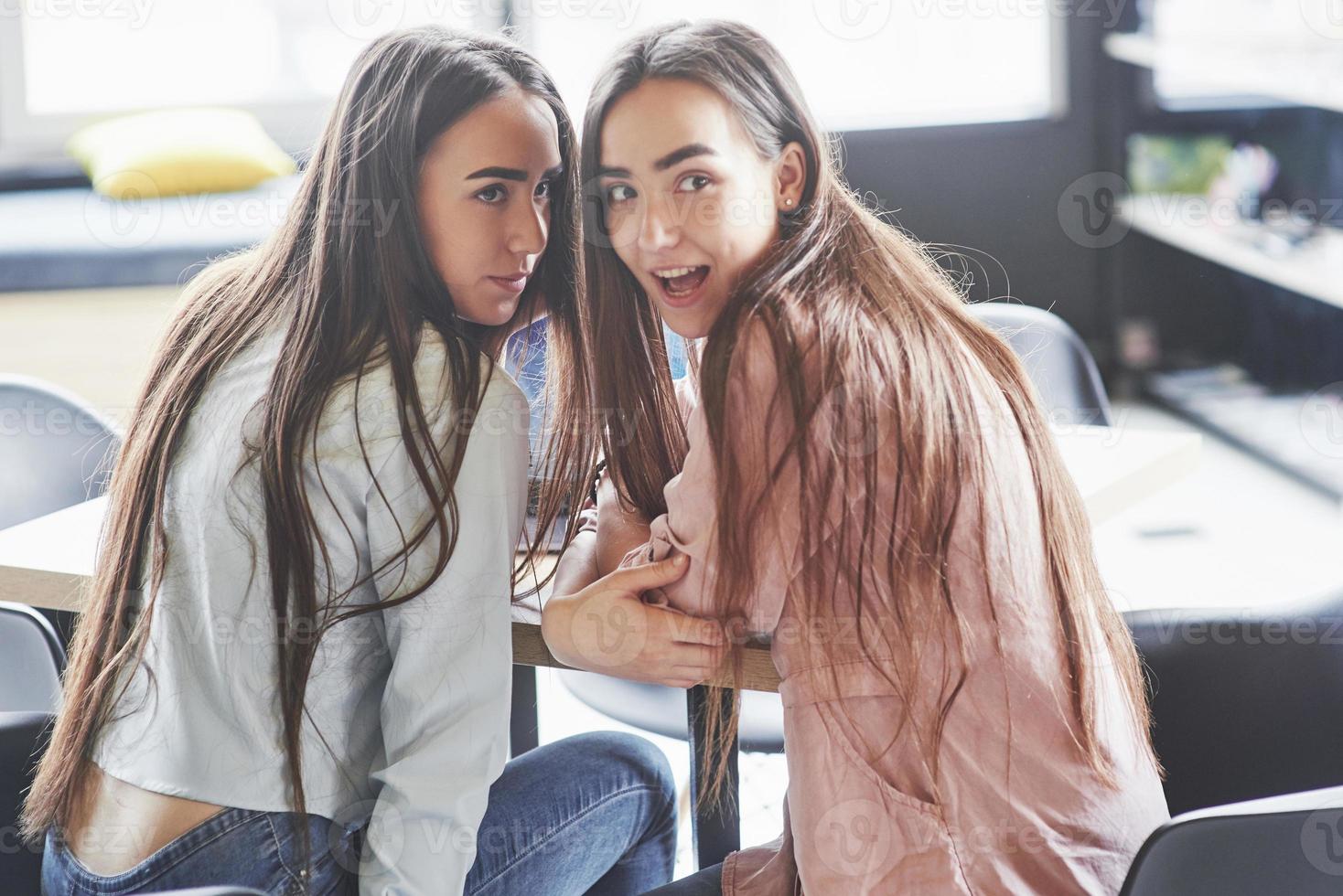 duas lindas gêmeas passam o tempo. irmãs relaxando em um café e se divertindo juntas e sussurrando foto