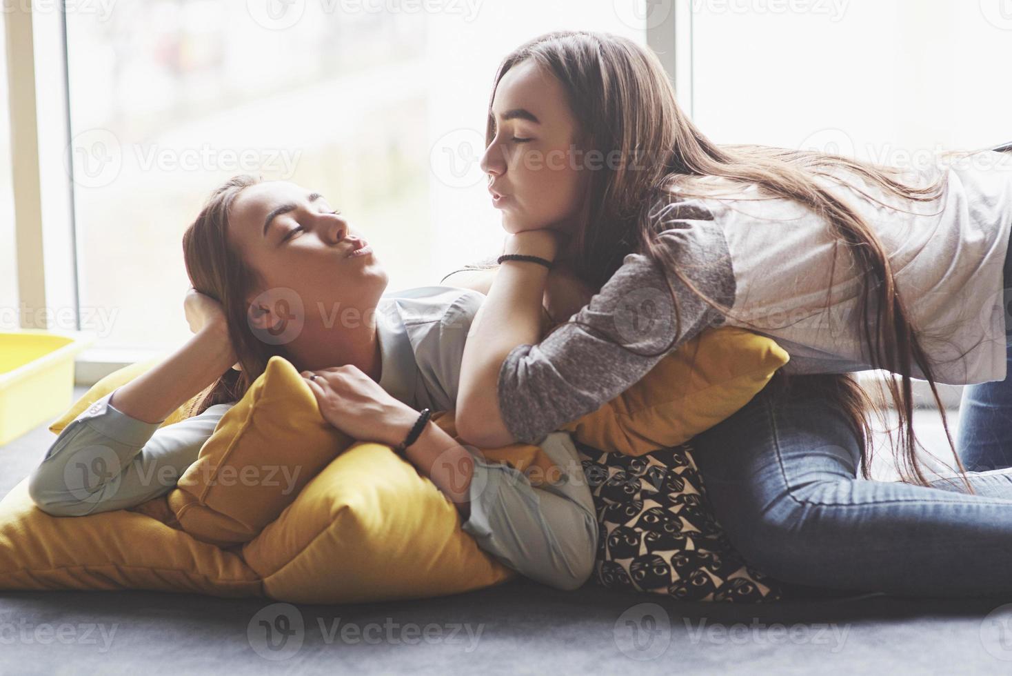 duas belas jovens irmãs gêmeas passando um tempo juntos com travesseiros. irmãos se divertindo em casa conceito foto