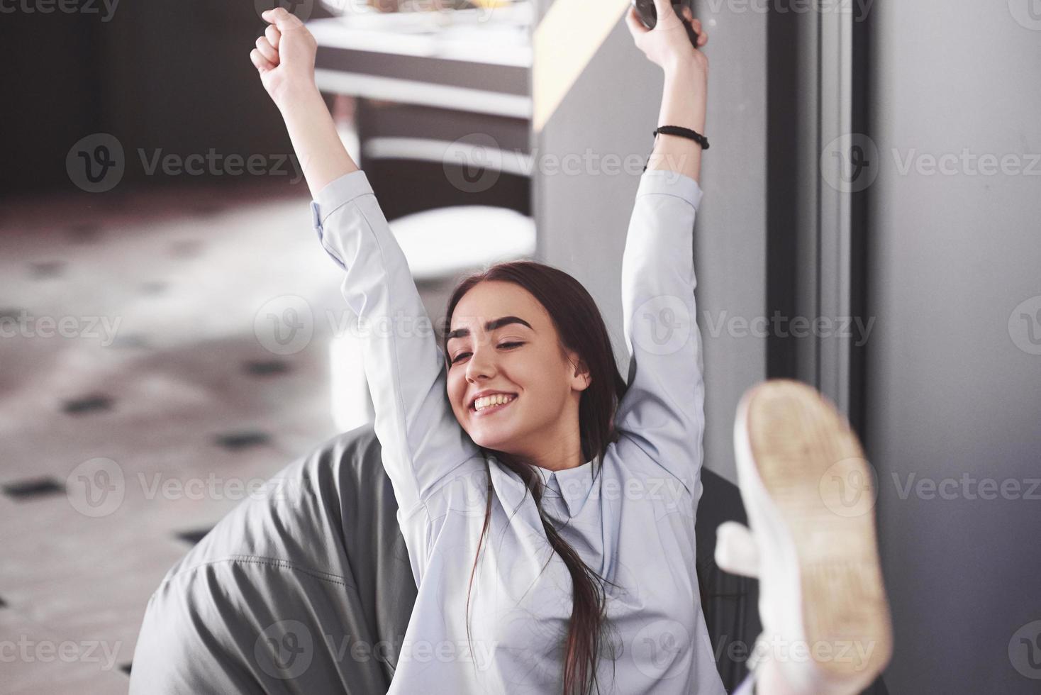 a mulher está jogando no console e fica feliz por ganhar, levanta os braços e sorri foto