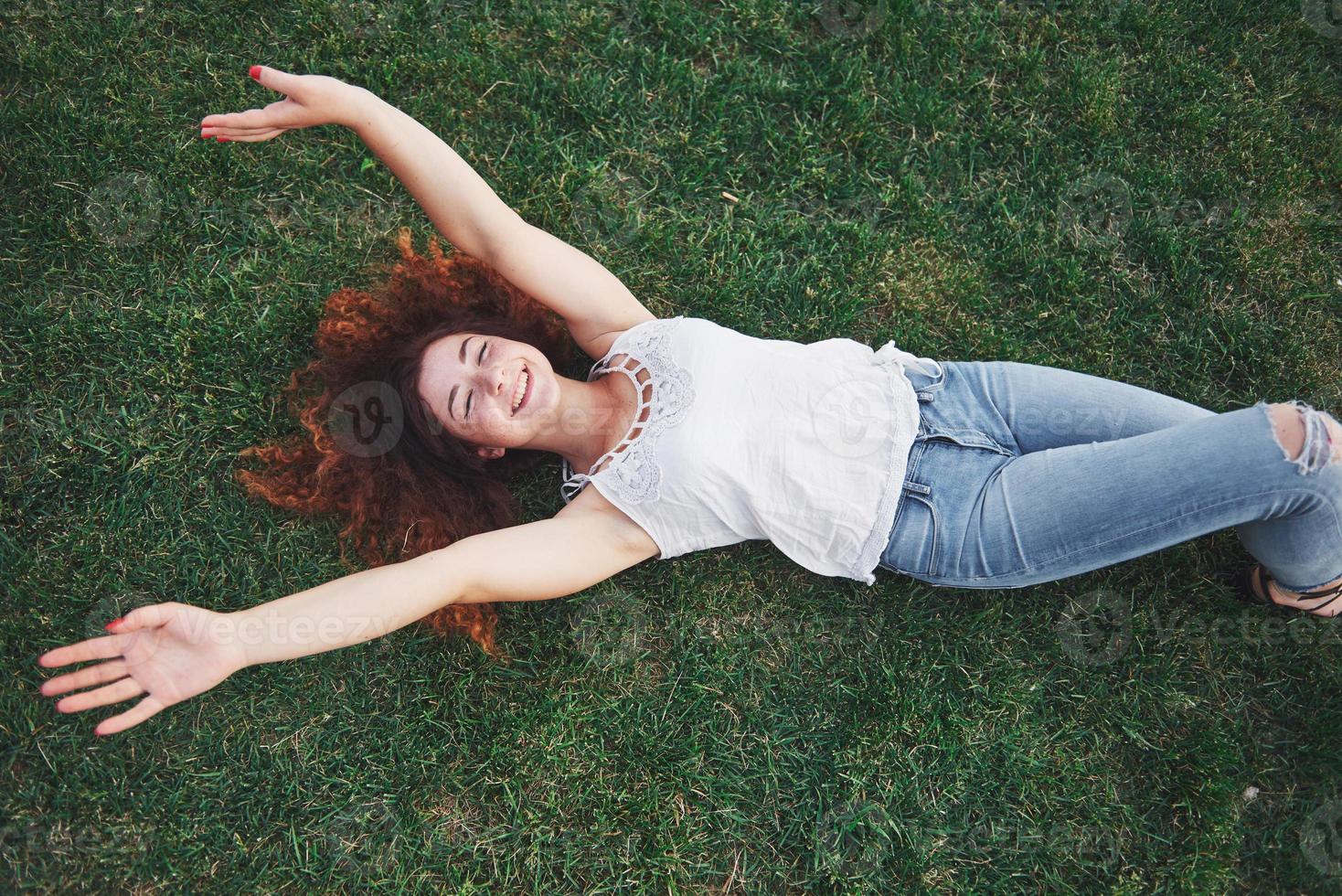 garota relaxante com vermelho, deitada na grama. mulher relaxa ao ar livre. foto