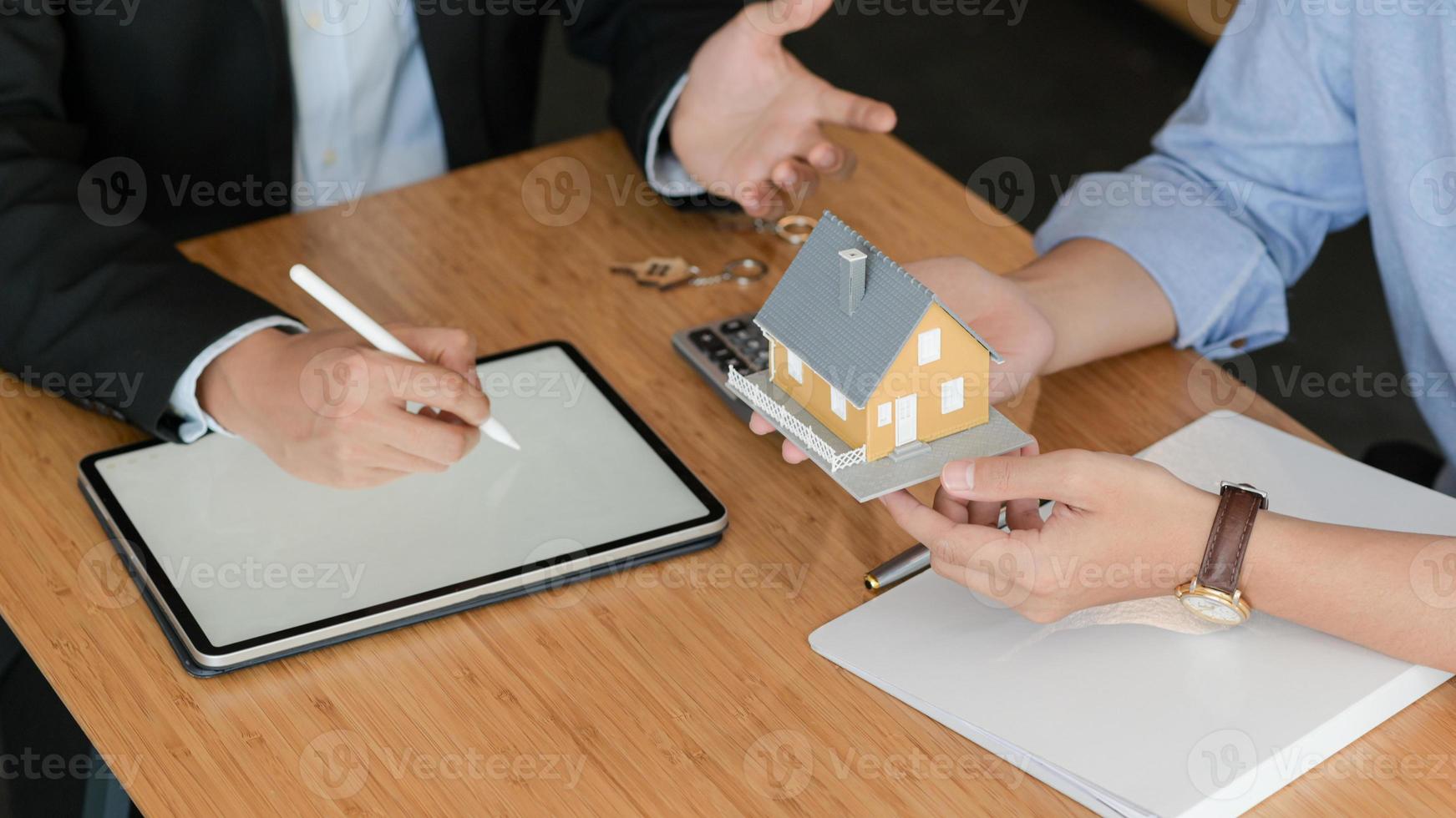 os clientes estão ouvindo promoções de home brokers. com casas modelo e tablet em cima da mesa. foto